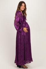 woman wearing a floral purple maxi maternity dress and holding her baby bump