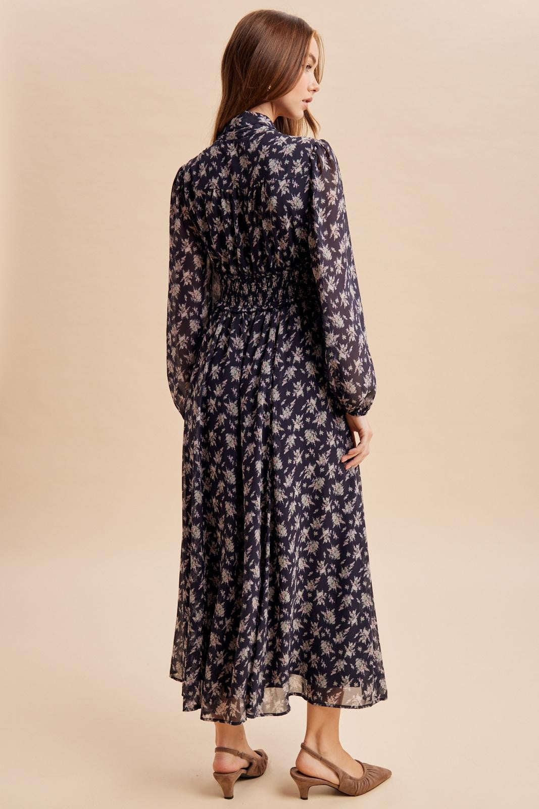 woman wearing a navy floral print long sleeve maxi dress with smocked waist and back view displayed
