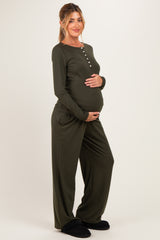 woman wearing an olive green long sleeve maternity loungewear set, holding her baby bump