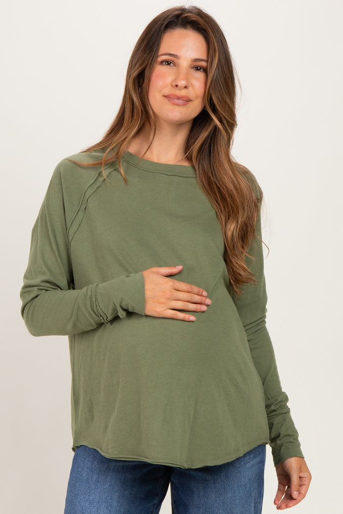 woman wearing a green long sleeve maternity top and holding her baby bump