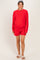 woman wearing a red maternity sweatshirt and matching shorts, smiling with a headband in her hair