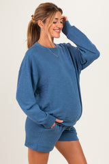 woman wearing a blue maternity loungewear set with a relaxed fit and pocketed shorts, showcasing her baby bump