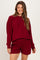 woman wearing a maroon maternity sweatshirt and matching shorts, smiling and styled casually