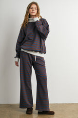 woman wearing a maroon and navy striped oversized sweatshirt and matching wide-leg pants, styled casually