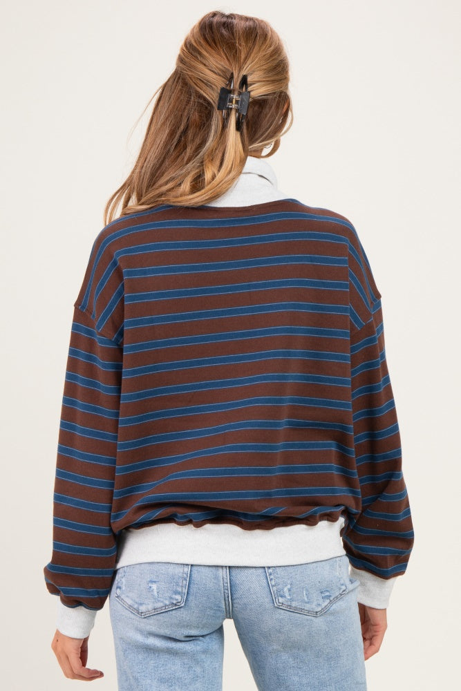 woman wearing a brown and blue striped maternity sweatshirt with a loose fit, showing a baby bump in light blue jeans