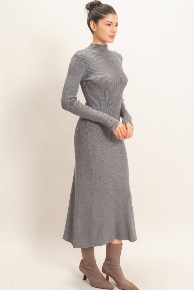 woman wearing a gray ribbed knit long sleeve midi dress with a high neckline and fitted silhouette, paired with beige ankle boots