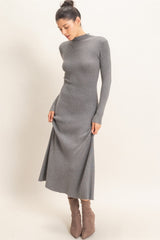 woman wearing a fitted gray ribbed maxi dress with long sleeves and a high neckline, paired with taupe ankle boots