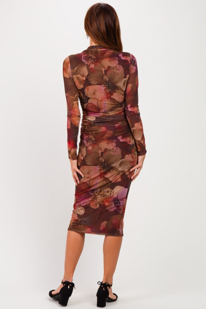woman wearing a fitted long sleeve floral print midi dress in earthy tones, showing the back view