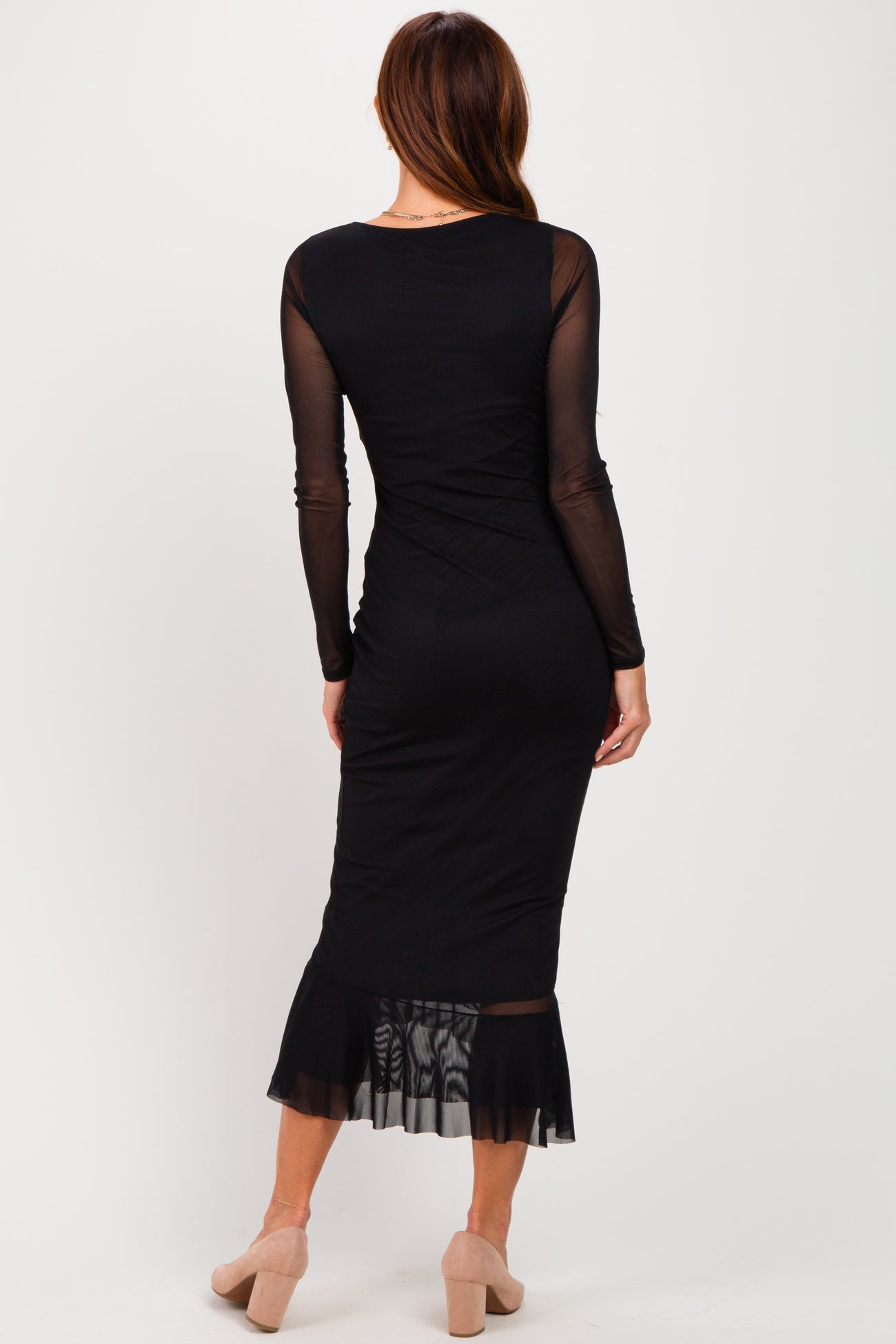 woman wearing a black long sleeve fitted dress with a sheer hem and back detailing
