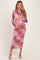 woman wearing a long pink floral maternity dress and holding her baby bump