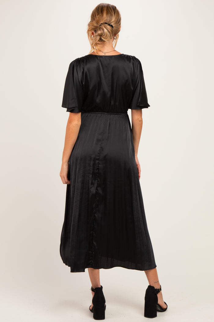 woman wearing a black satin maternity dress with short sleeves and a pleated skirt, showing a baby bump from the back