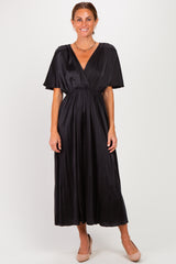 woman wearing a black satin maxi dress with a deep v-neck and short flutter sleeves, standing in a neutral pose