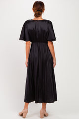 woman wearing a black pleated midi dress with a cinched waist and short sleeves, view from the back