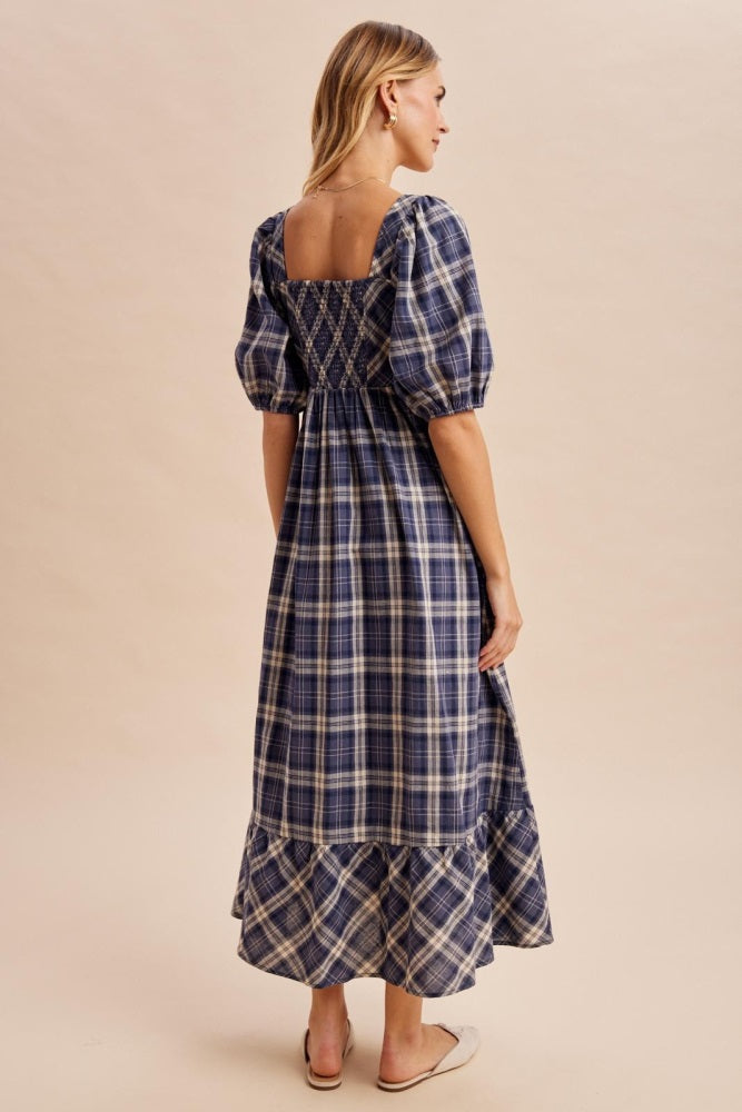 woman wearing a navy blue and white plaid maxi dress with puff sleeves and a smocked back detail