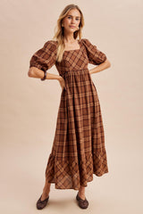 woman wearing a brown plaid puff sleeve maxi dress with a square neckline and tiered ruffle hem
