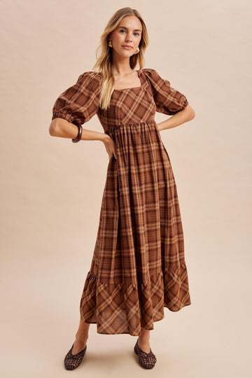 woman wearing a brown plaid puff sleeve maxi dress with a square neckline and tiered ruffle hem