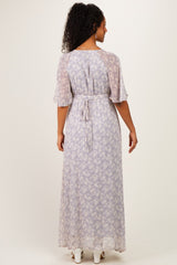 woman wearing a light purple floral maternity maxi dress with short sleeves and a tie waist, showing a baby bump