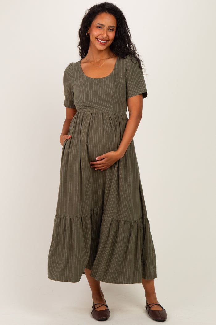 woman wearing a green striped maternity dress with short sleeves and a tiered skirt, holding her baby bump
