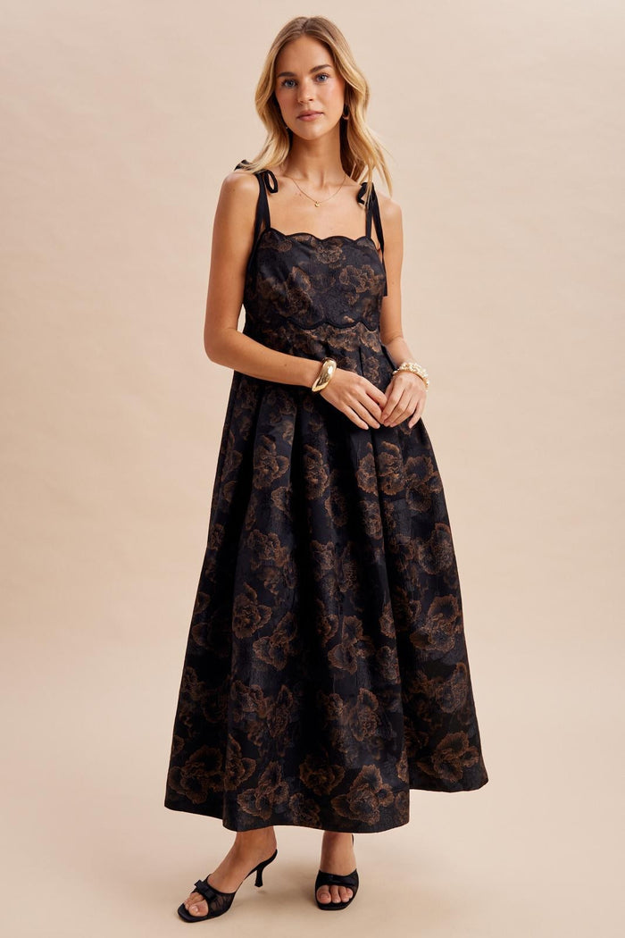 woman wearing a black floral print maxi dress with shoulder straps and a fitted bodice, styled with black heels
