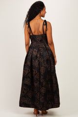 woman wearing a black maternity maxi dress with brown floral pattern and tie straps, showing the back view and no baby bump visible