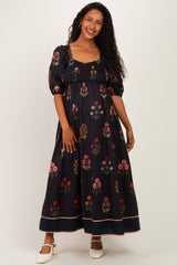 woman wearing a black floral maternity maxi dress with puff sleeves and a square neckline, displaying a baby bump