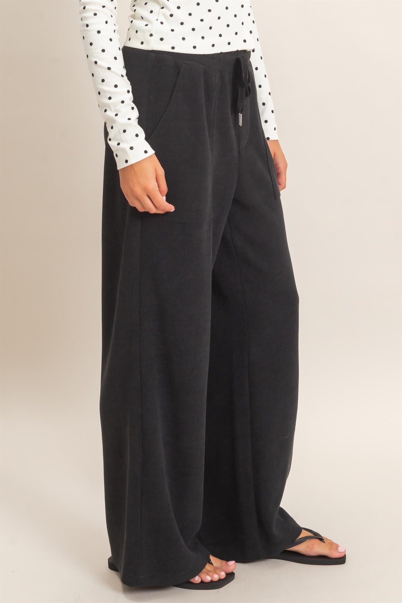 woman wearing black wide-leg lounge pants paired with a white polka dot long sleeve top