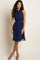woman wearing a navy blue sleeveless halter neck dress with a cinched waist and tan heels