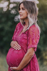 woman wearing a pink embroidered maternity dress and holding her baby bump