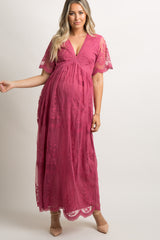 woman wearing a pink embroidered maternity maxi dress, holding her baby bump, with short sleeves and a flowy silhouette