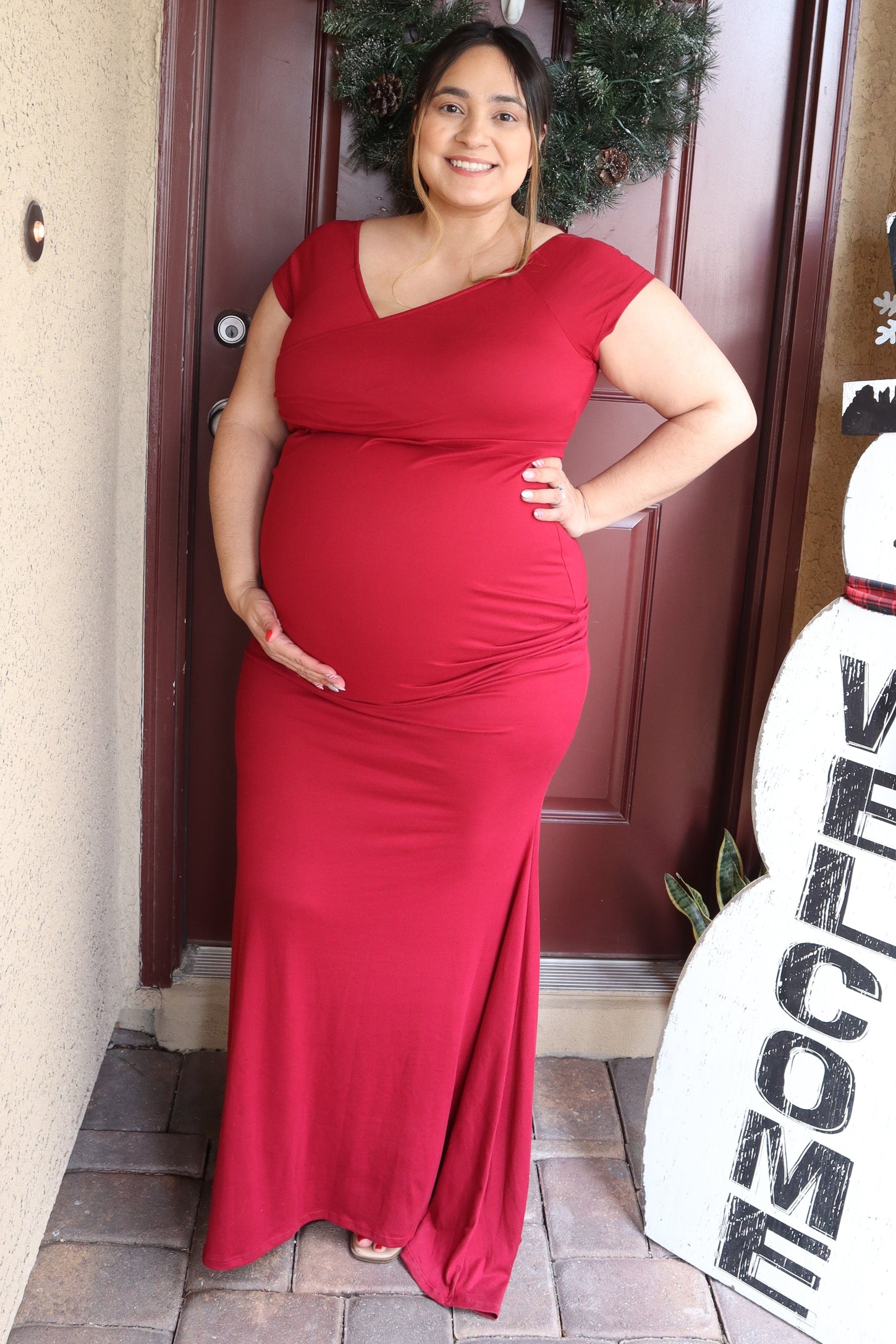 woman wearing a red maternity maxi dress and holding her baby bump