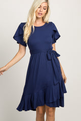 woman wearing a navy blue short sleeve dress with a tie at the waist and a flared skirt, smiling outdoors
