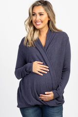 smiling woman wearing a navy blue long sleeve draped wrap top and dark wash jeans