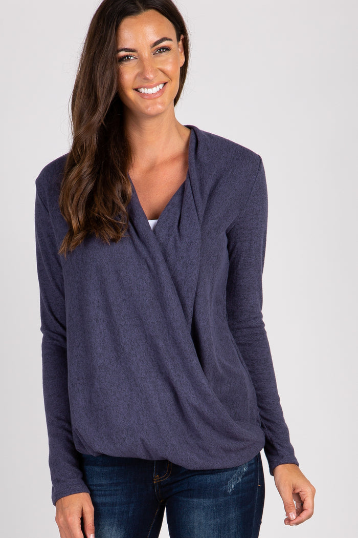 smiling woman wearing a navy blue long sleeve draped wrap top and dark wash jeans