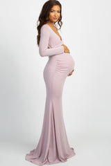 woman wearing a light pink off-shoulder maternity dress and holding her baby bump