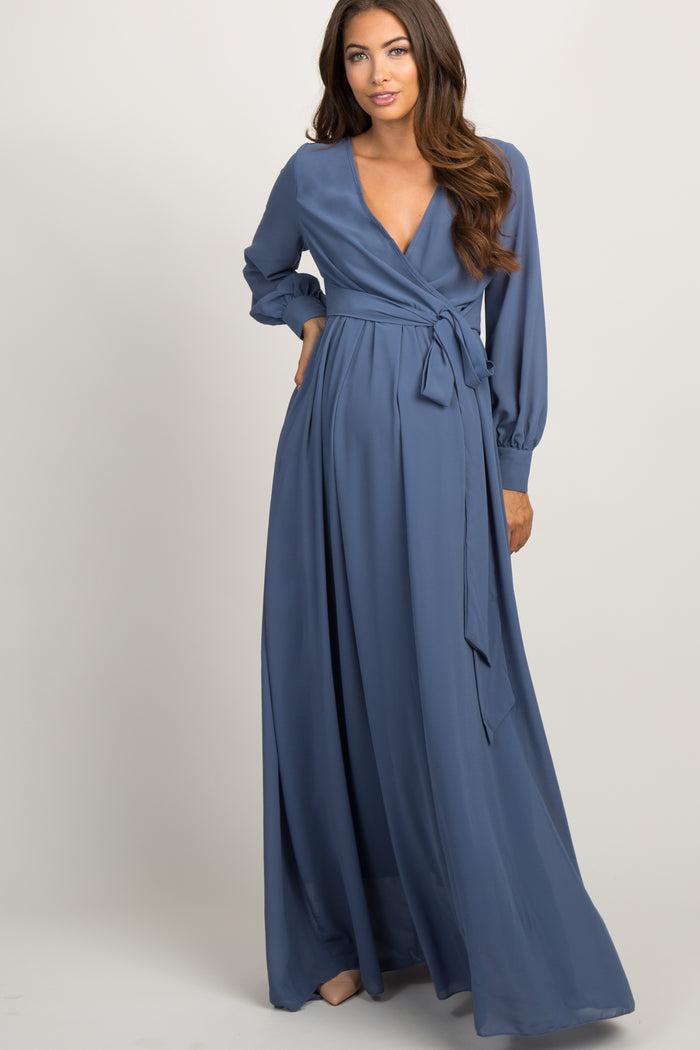 woman wearing a long sleeve blue maternity maxi dress with a wrap front and waist tie