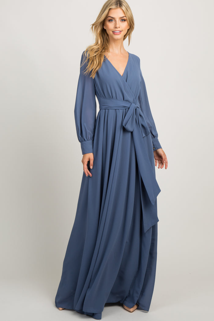 woman wearing a long sleeve blue maternity maxi dress with a wrap front and waist tie