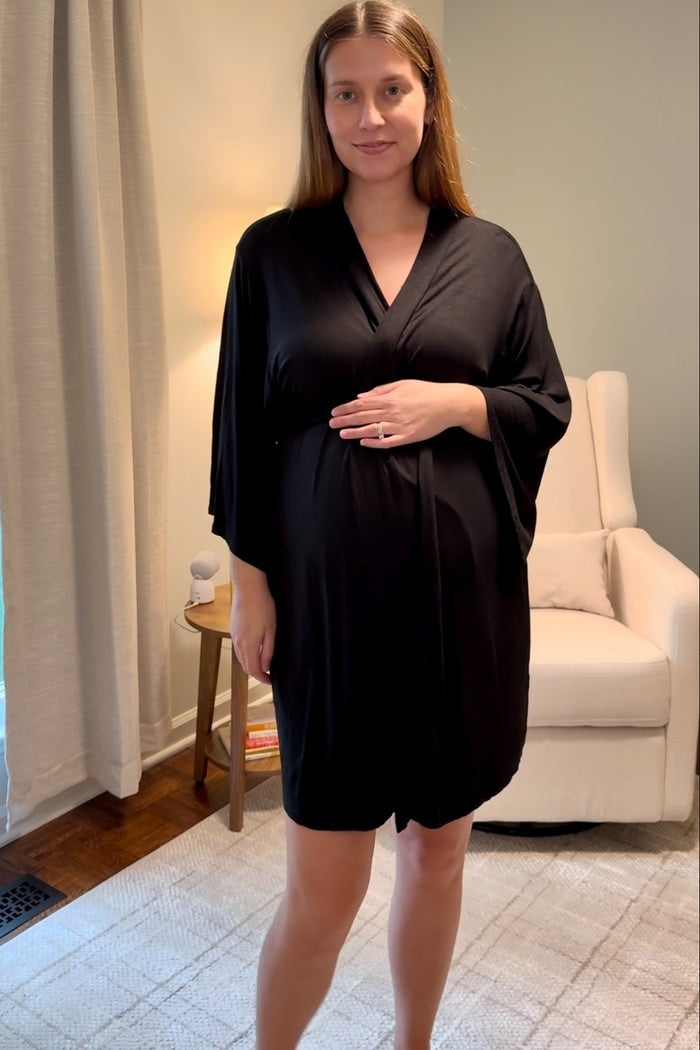 woman wearing a black maternity robe and holding her baby bump in a living room setting