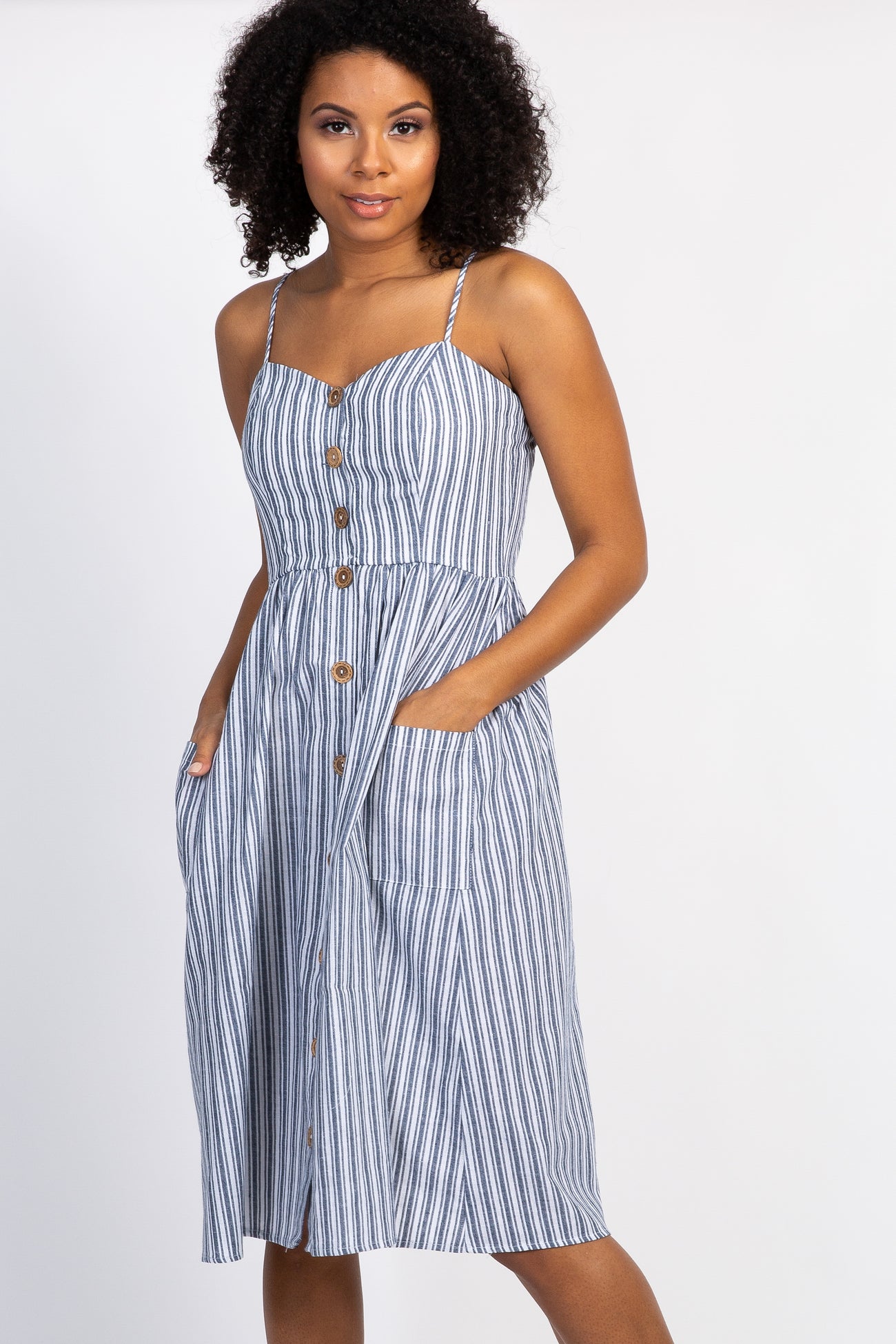 woman wearing a blue and white striped midi dress with buttons and pockets against a white background