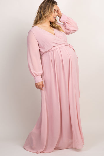 woman wearing a long sleeve light pink chiffon maxi dress with a belted waist