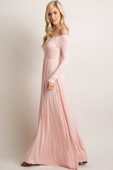 woman wearing a soft pink off-the-shoulder maxi dress with long sleeves and a flowing silhouette