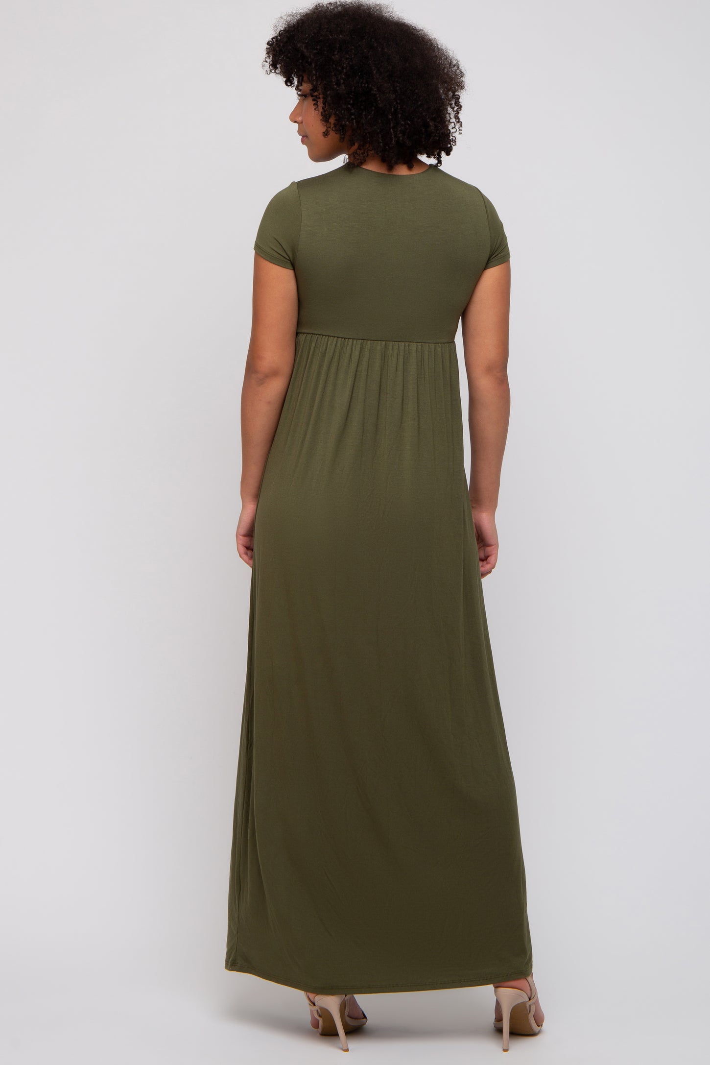 woman wearing a dark olive green short sleeve maxi dress with a flowy back design