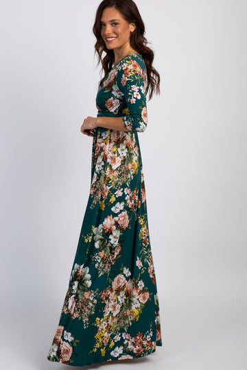 woman wearing a floral print long sleeve maxi dress in teal with a fitted waist and flowy skirt