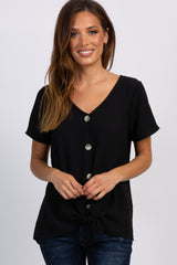 woman wearing a black short sleeve button down top with a front tie knot and blue jeans
