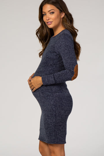 woman wearing a navy blue long sleeve maternity dress with elbow patch detailing and holding her baby bump