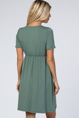woman wearing a short sleeve olive green dress with a cinched waist and a flared skirt, seen from the back