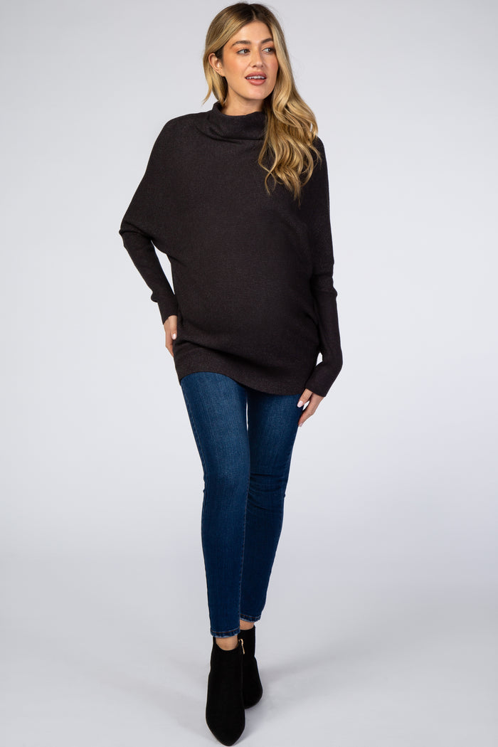 woman wearing a dark gray maternity poncho with a cowl neck and blue skinny jeans, showcasing her baby bump