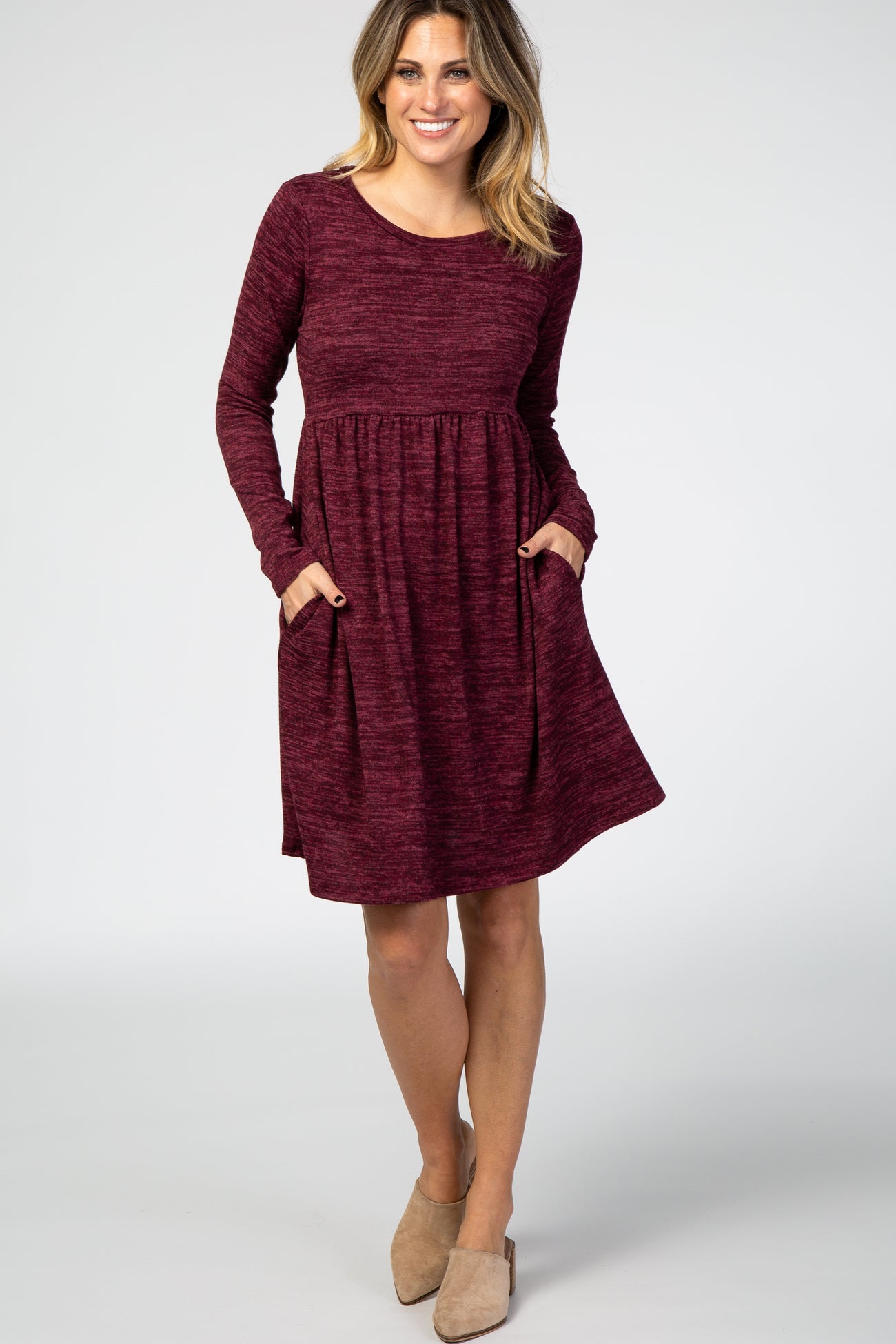 woman wearing a burgundy long sleeve dress with side pockets and a relaxed fit