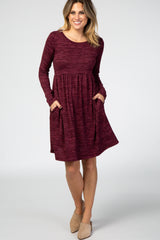 woman wearing a burgundy long sleeve dress with side pockets and a relaxed fit