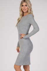 woman wearing a form-fitting grey ribbed sweater dress with long sleeves