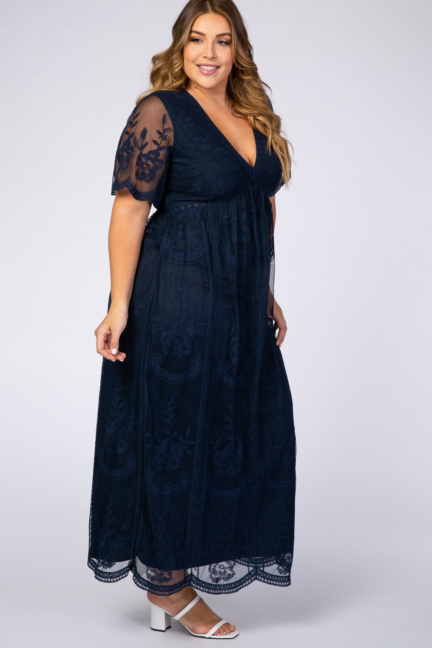 woman wearing a navy blue plus size maxi dress with floral embroidery and short sheer sleeves